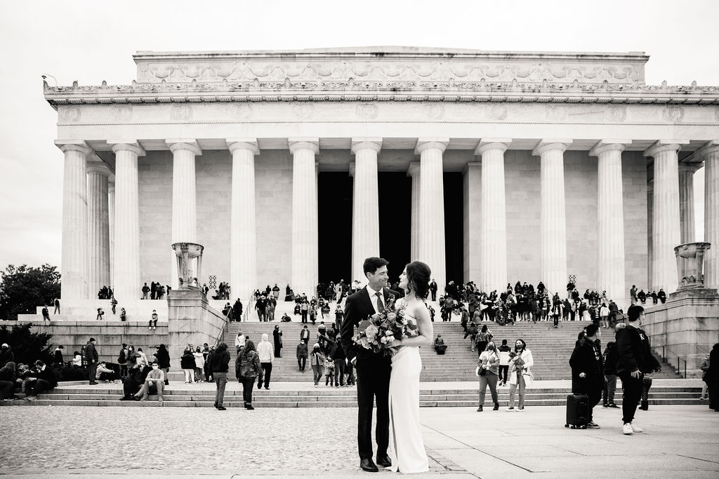 a couple standing in front of a monument in washington dc taking couple wedding portraits 
