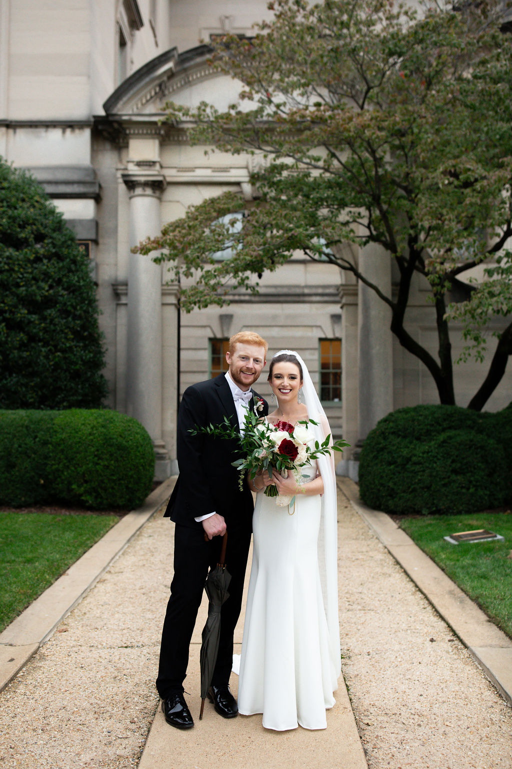 a couple standing together on the day of their wedding smiling the woman is holding a bouquet of flowers 