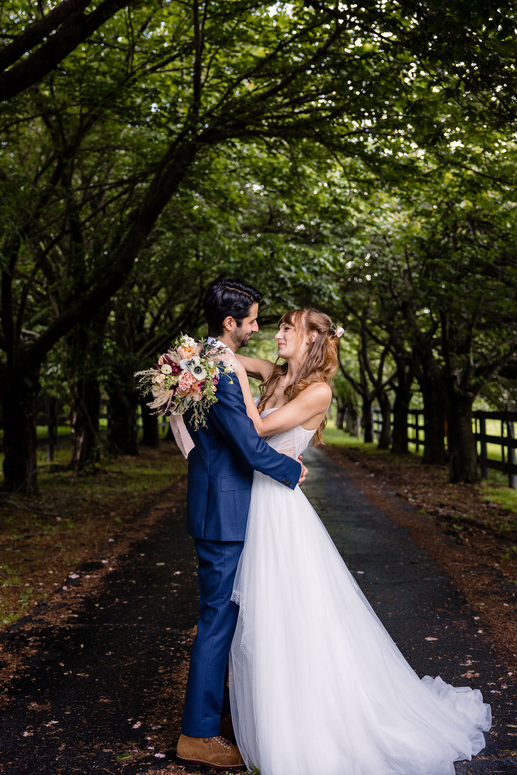a couple embracing in apark on the day of their wedding 