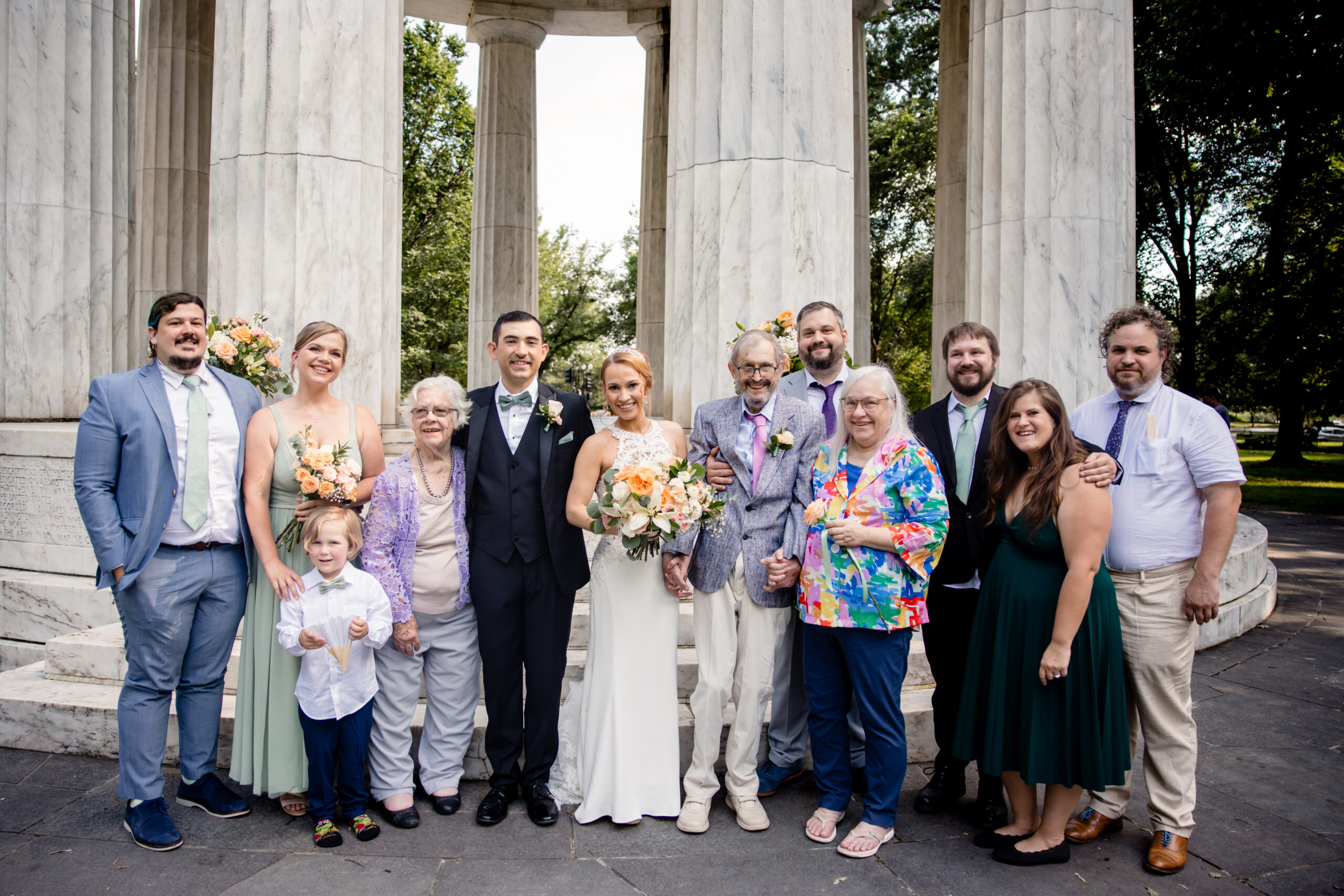 a family together taking family wedding photos in front of a pavilion 