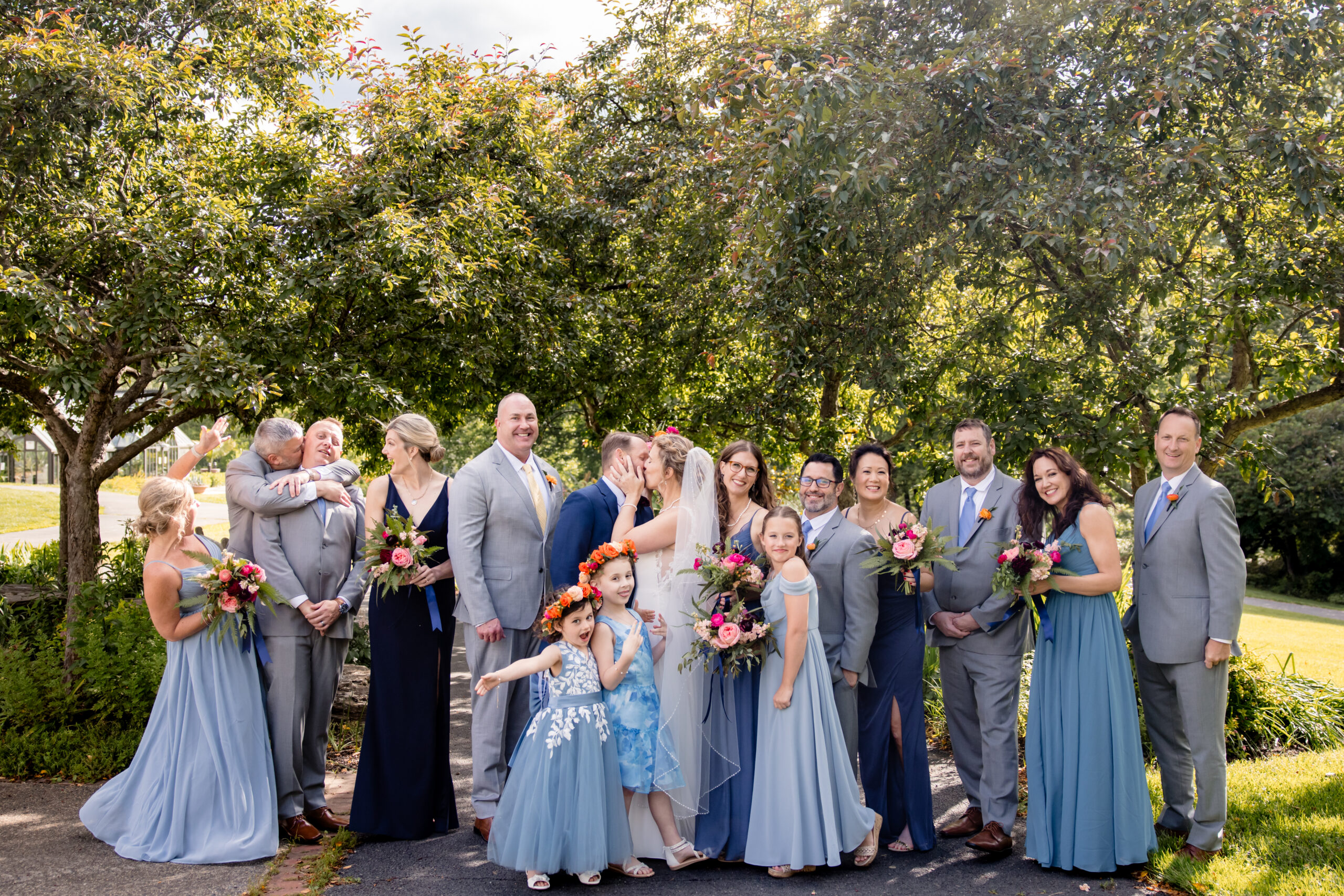 a bride and groom kissing taking photos with their wedding party and family 