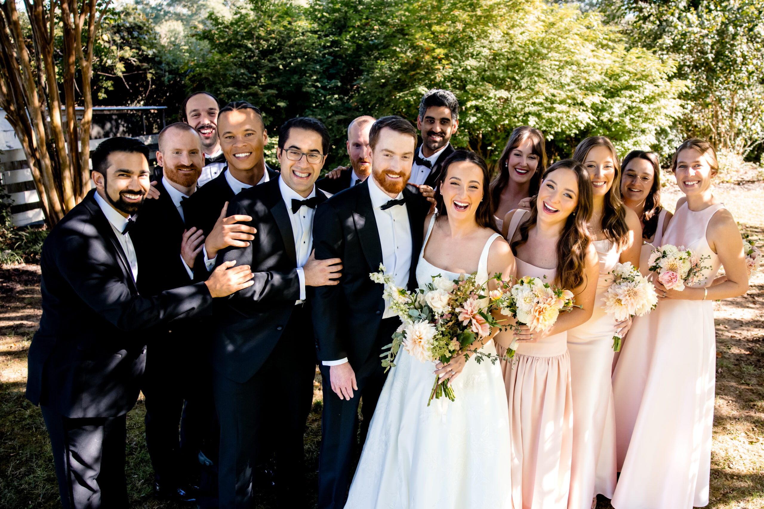 a bride and groom with their wedding parties taking a group photo 