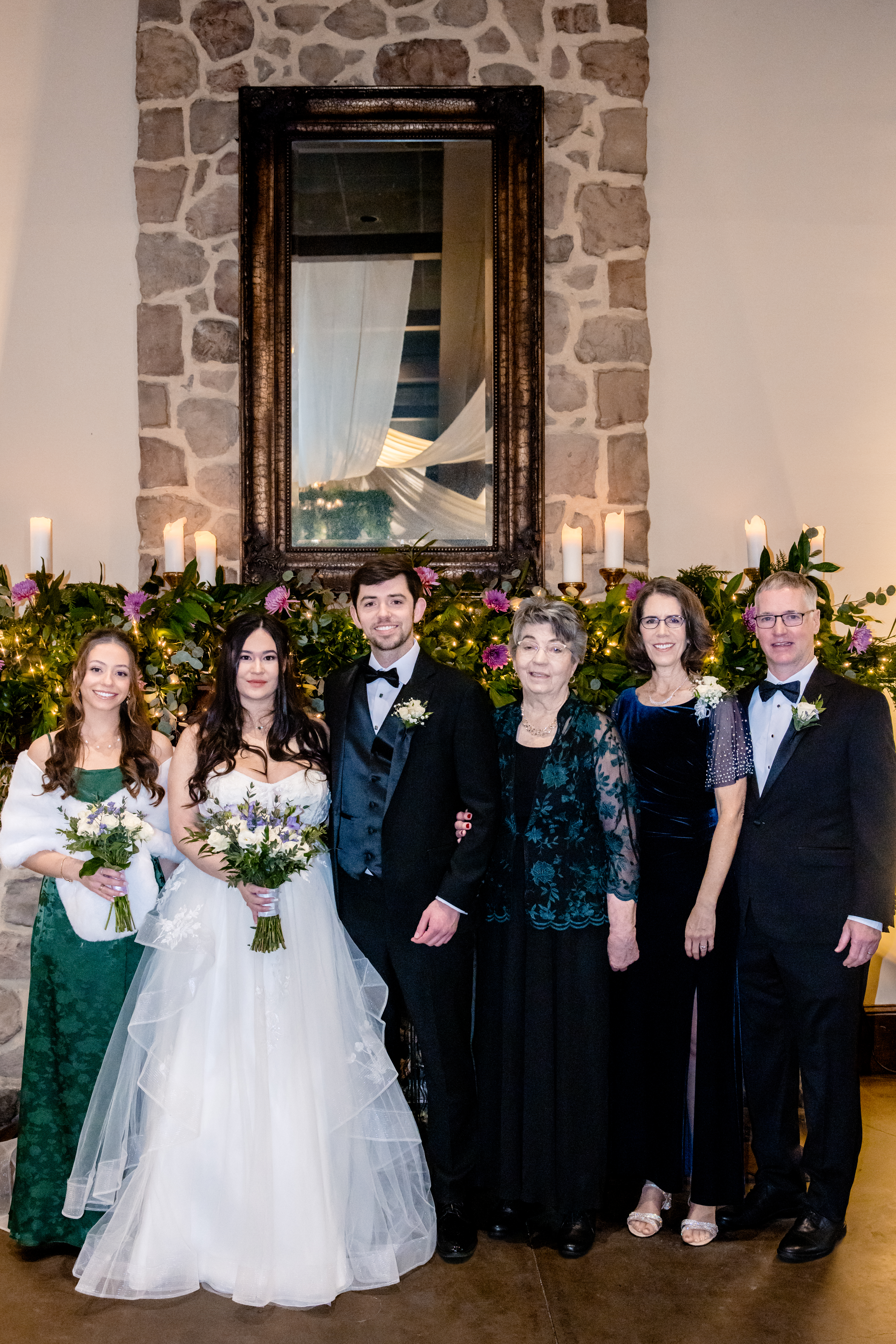 a bride and groom taking family wedding photos with their family in front of a fireplace