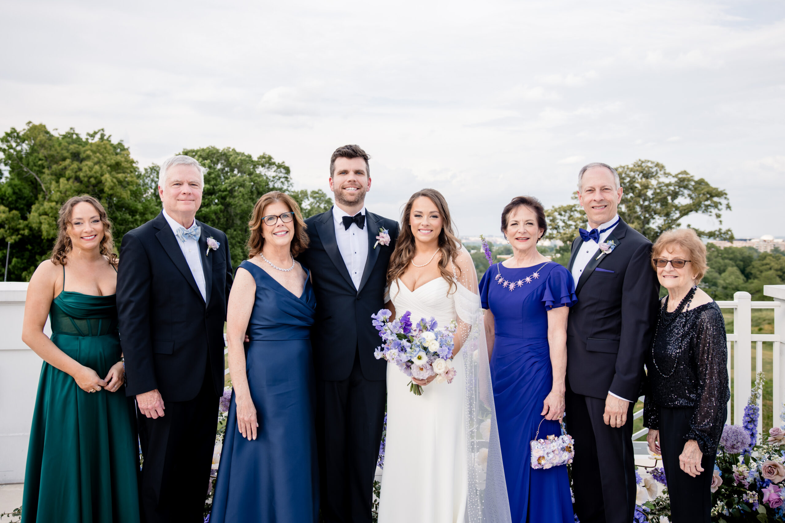 a bride and groom taking family wedding photos with their family on a deck 