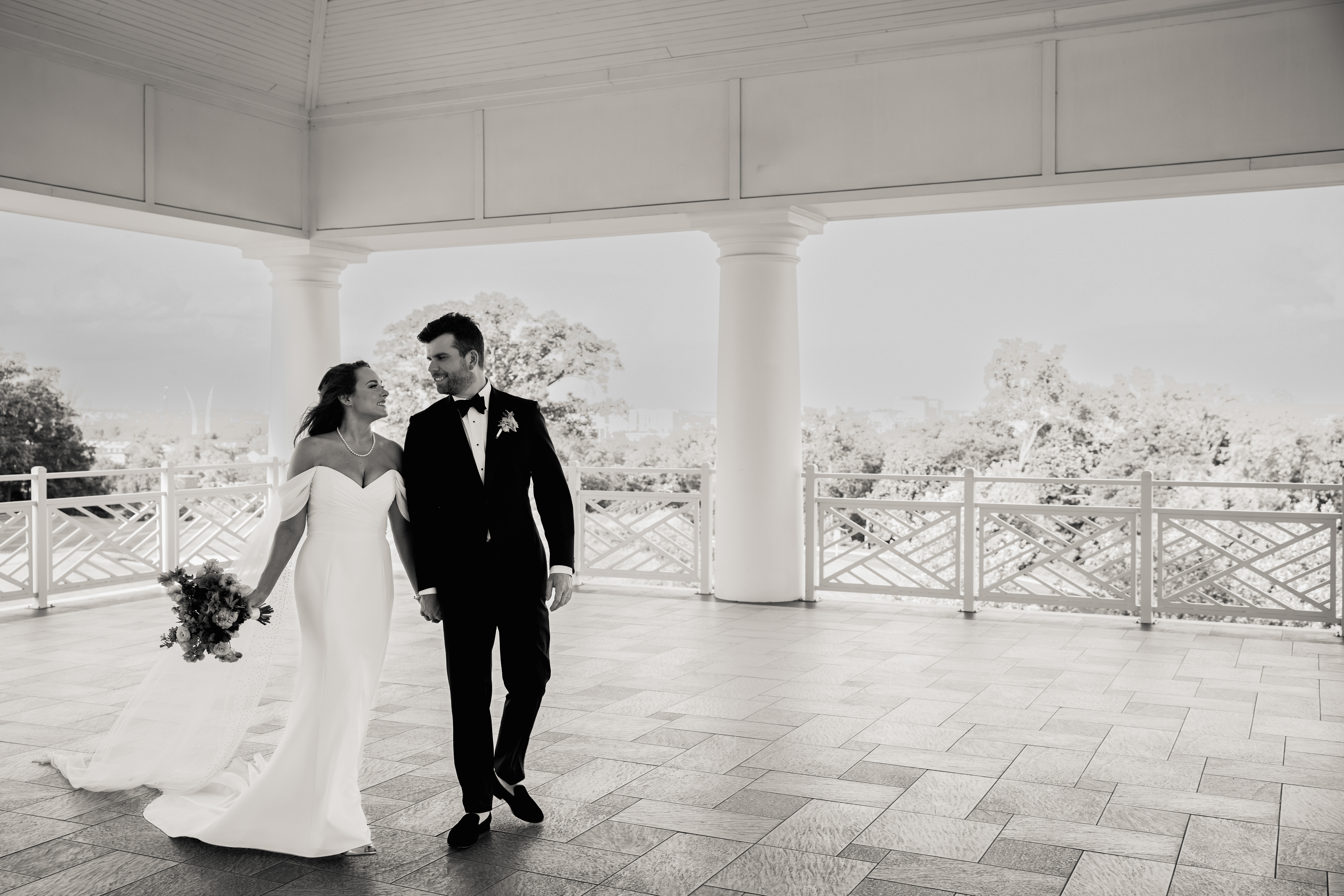 a bride and groom walking hand in hand across a pavilion 