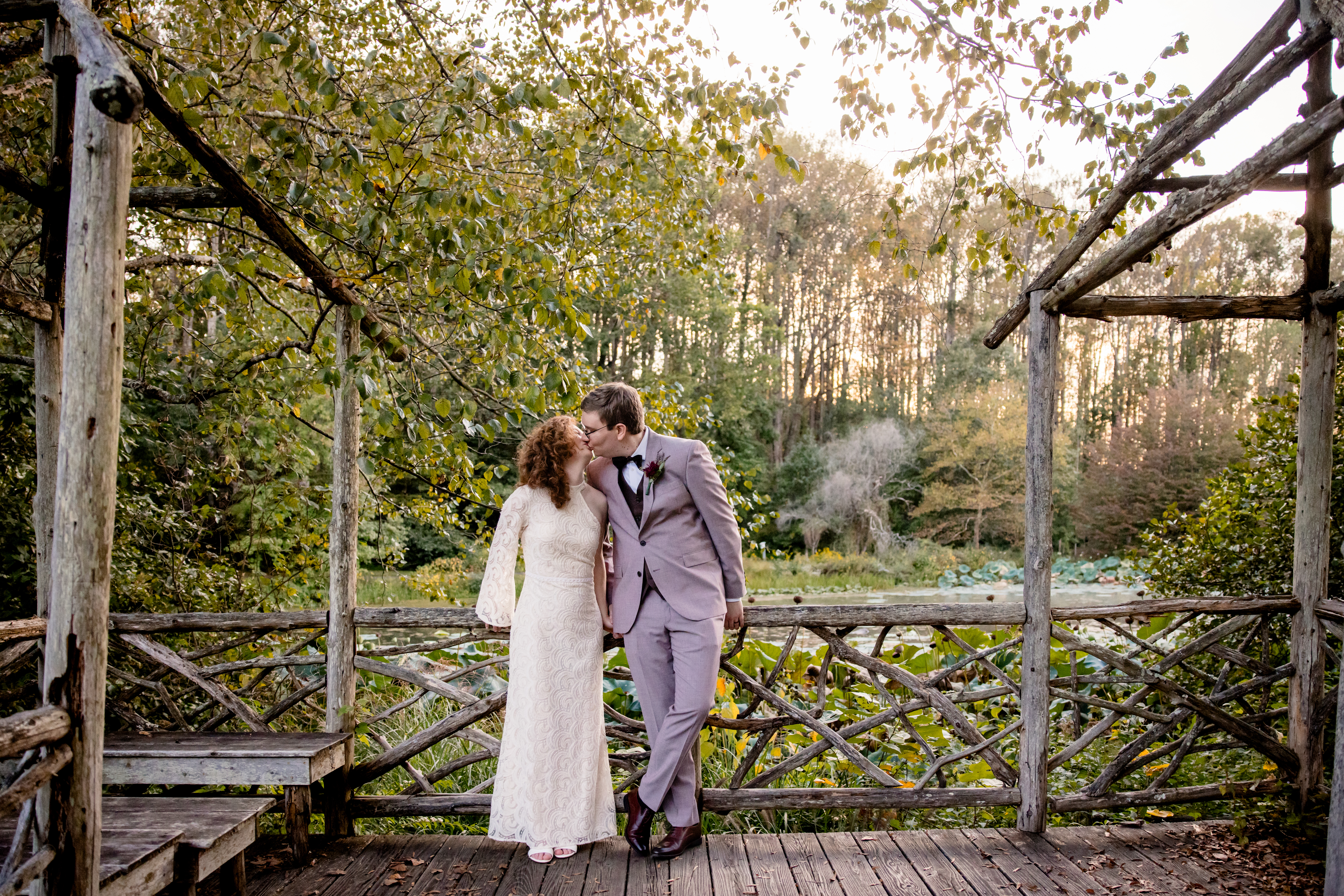 a bride and groom kissing each other on a wooden bridge surrounded by forest 