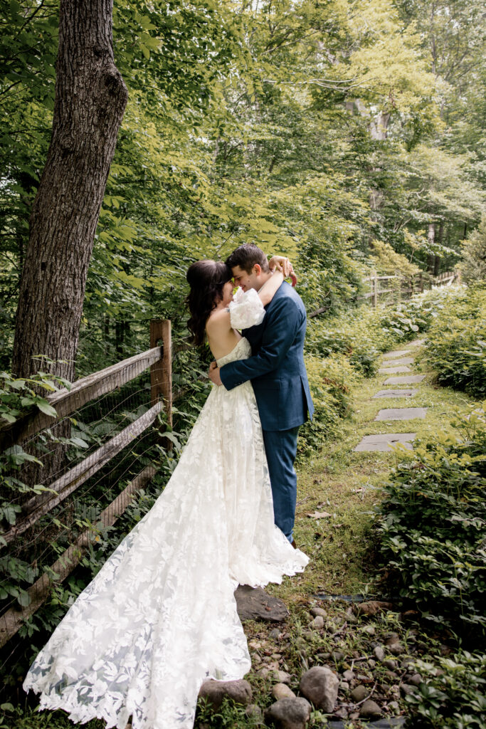 a couple embracing their wedding day on a path surrounded by trees 