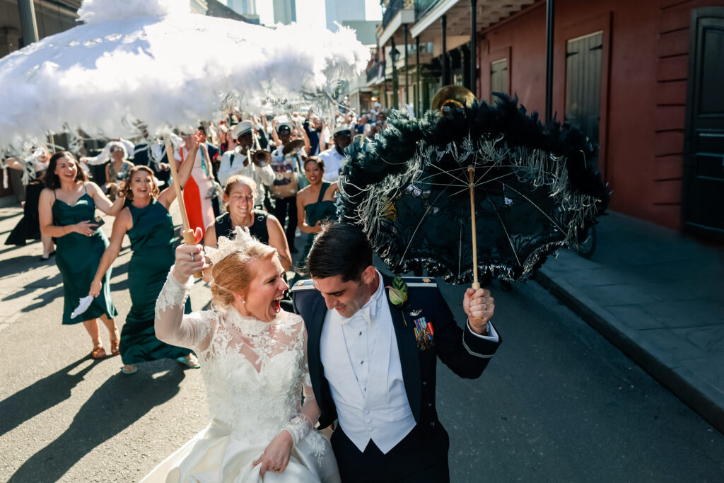 Newlyweds and their wedding guests parading down a city street 