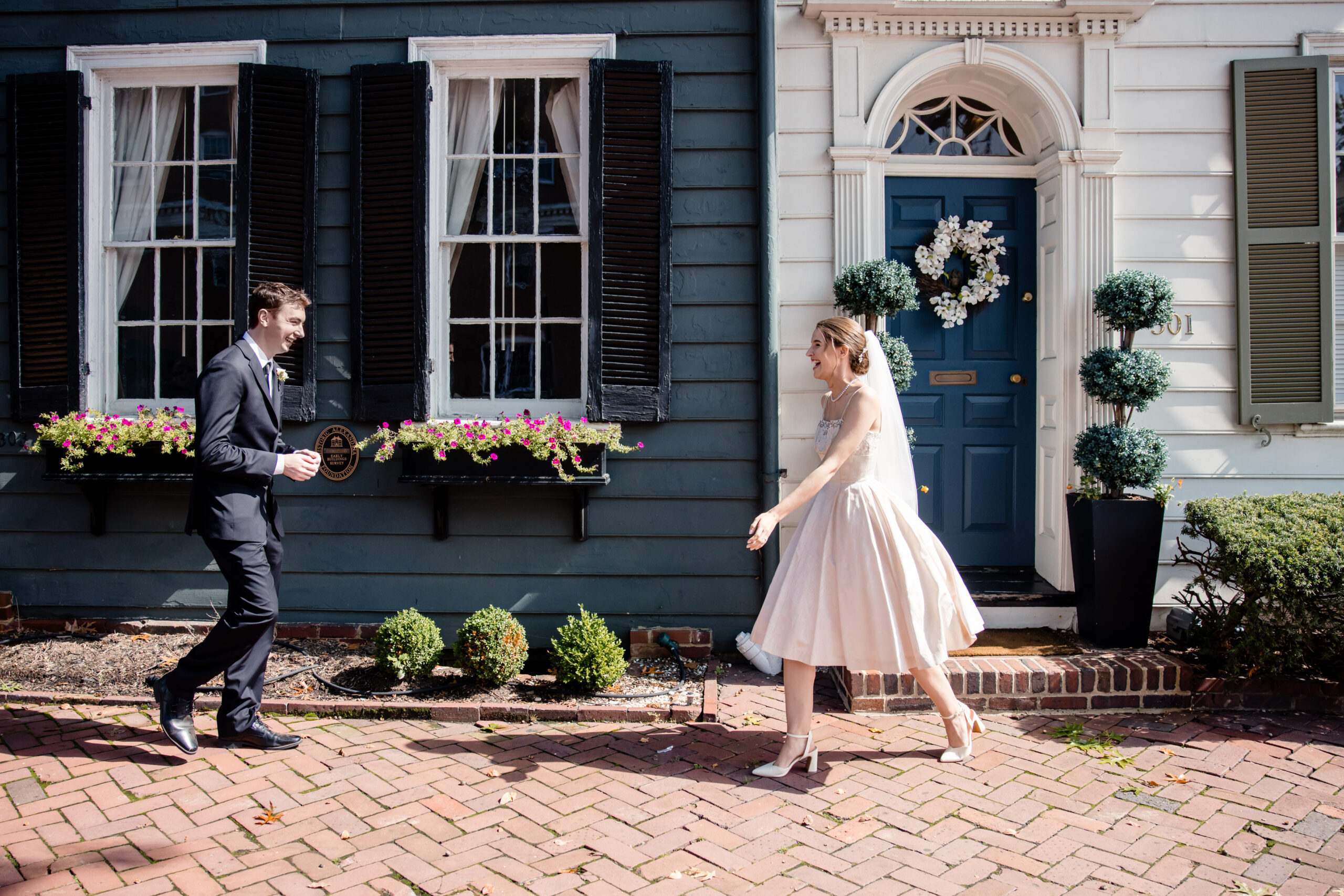 a couple walking towards each other as they share a first look together in front of their home