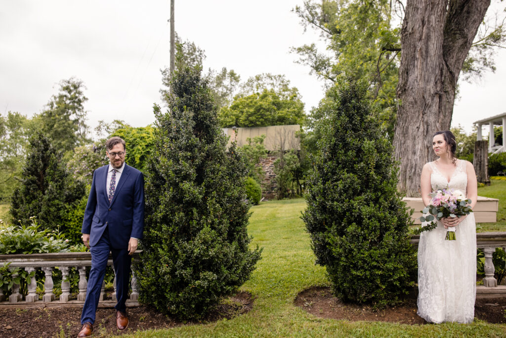 a couple standing side by side together in a garden about to share a first look with each other on the day of their wedding