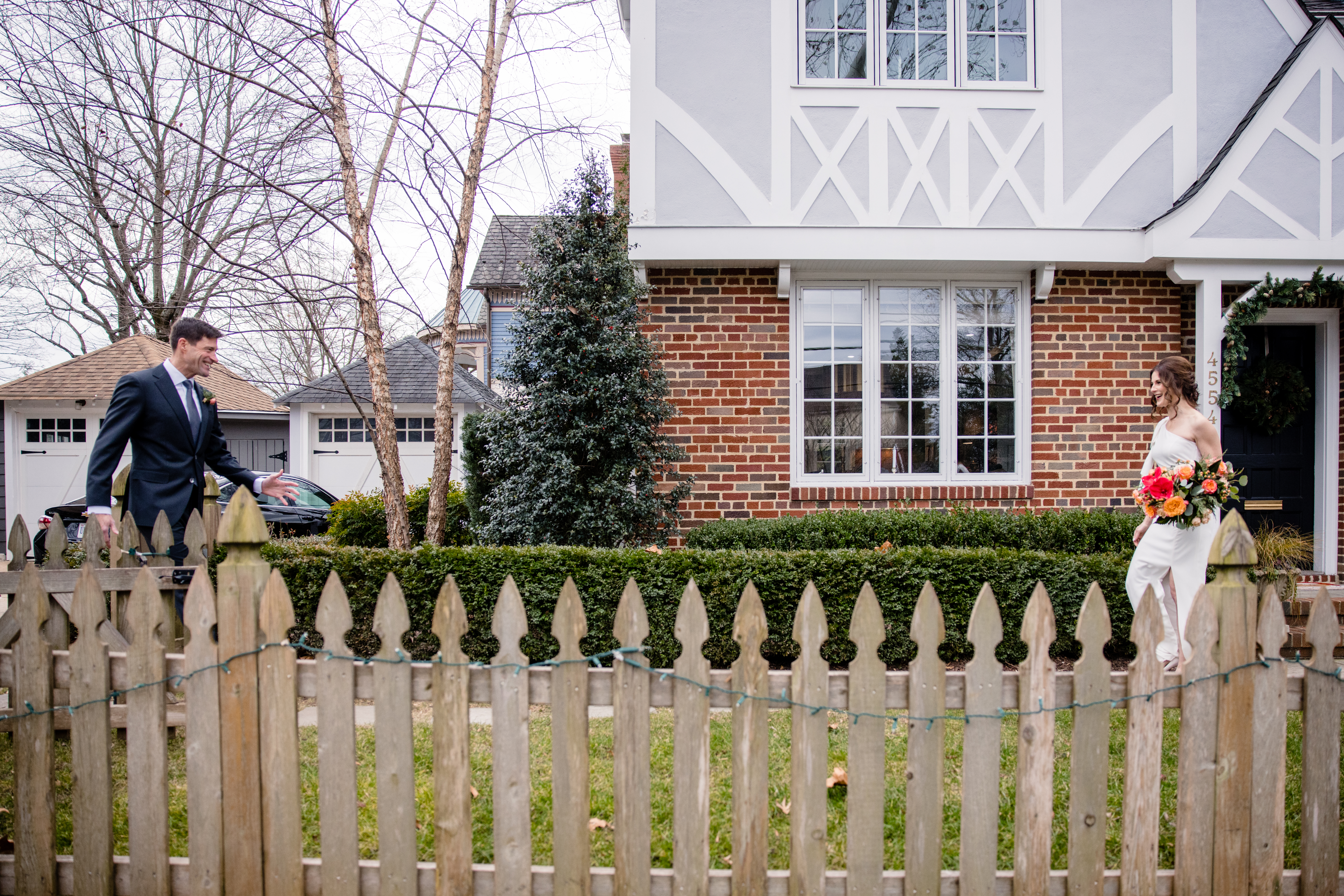 a couple walking down a sidewalk in front of a house sharing a first look with each other on the day of their wedding