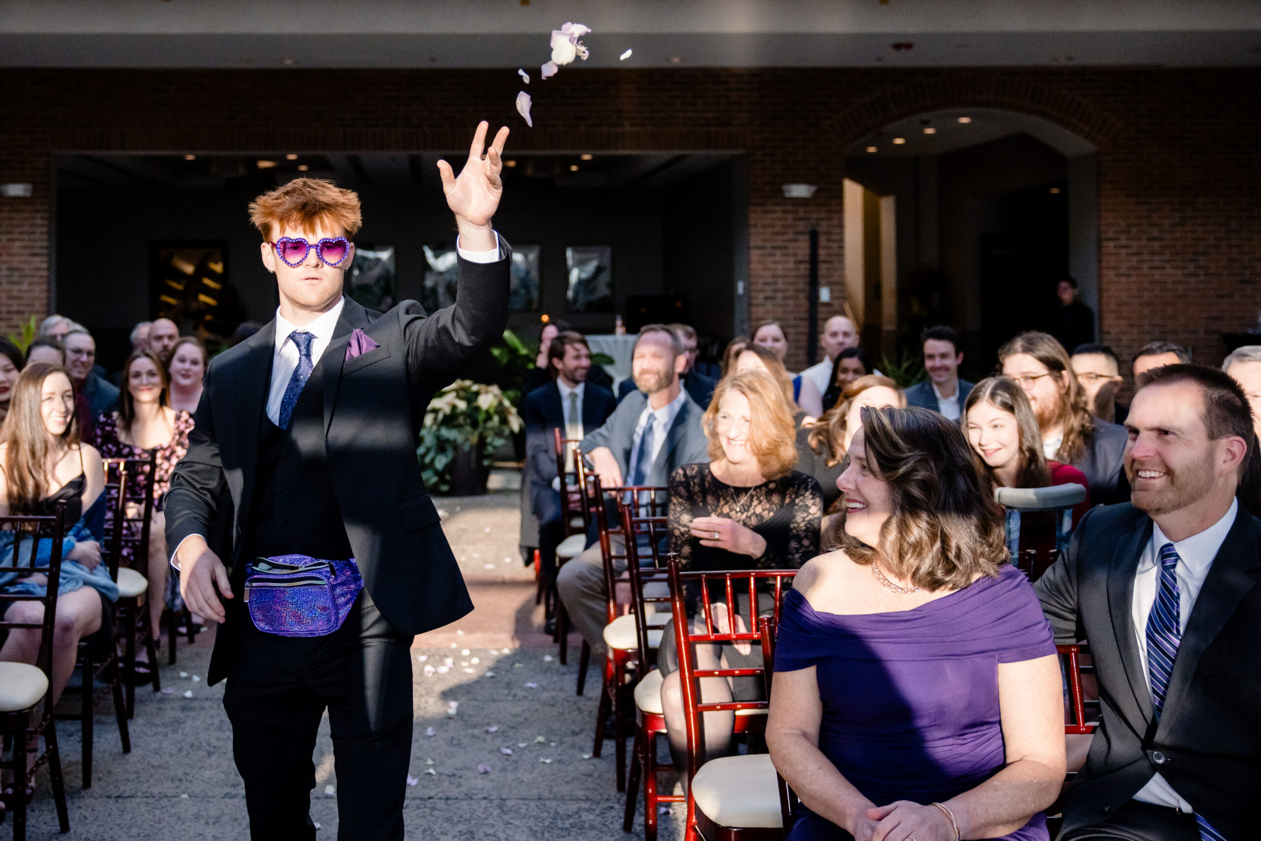 a man throwing flower petals at a wedding ceremony in front of the wedding guests 