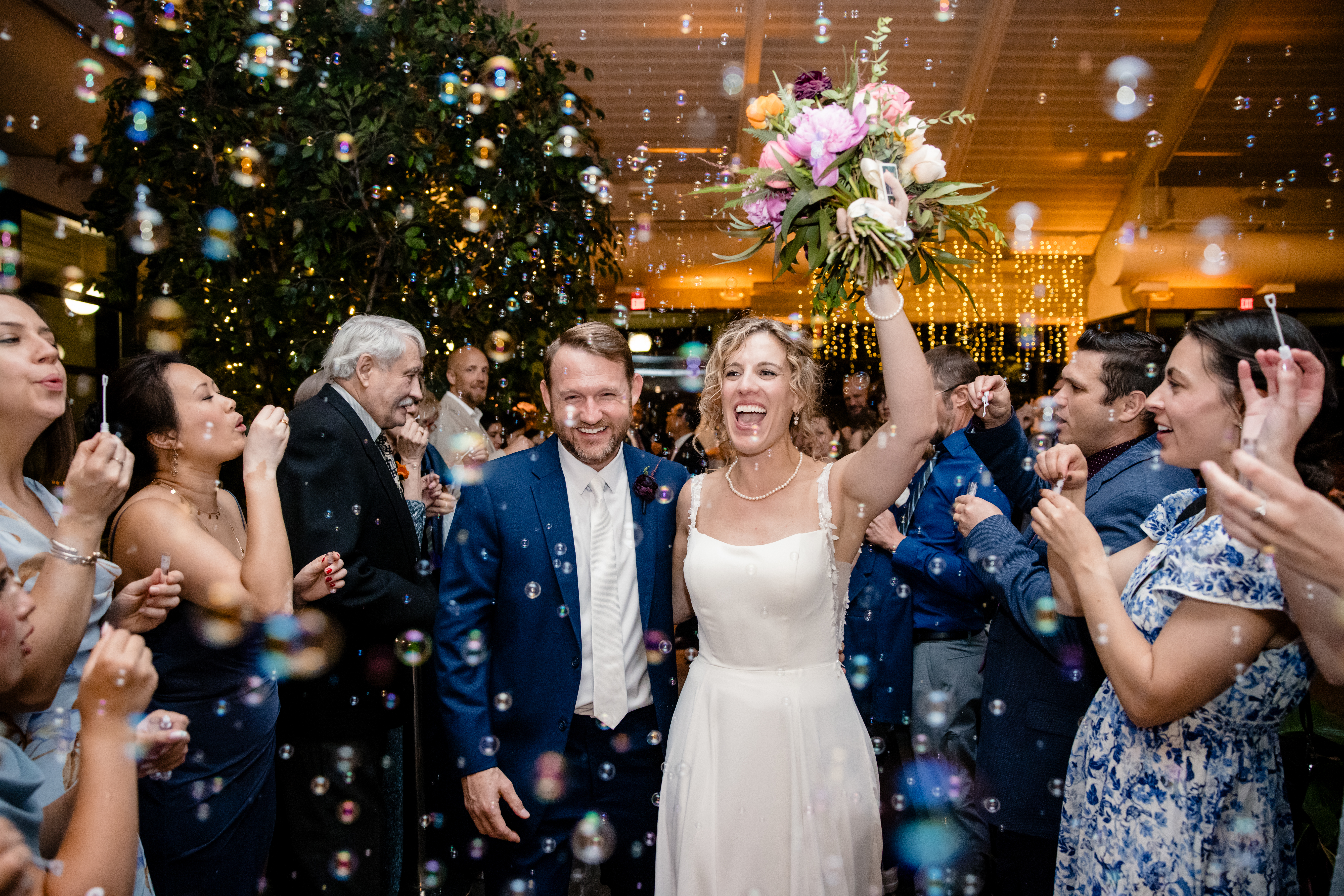 a man and woman having their wedding reception at The Atrium at Meadowlark Botanical Gardens while their guests blow bubbles 