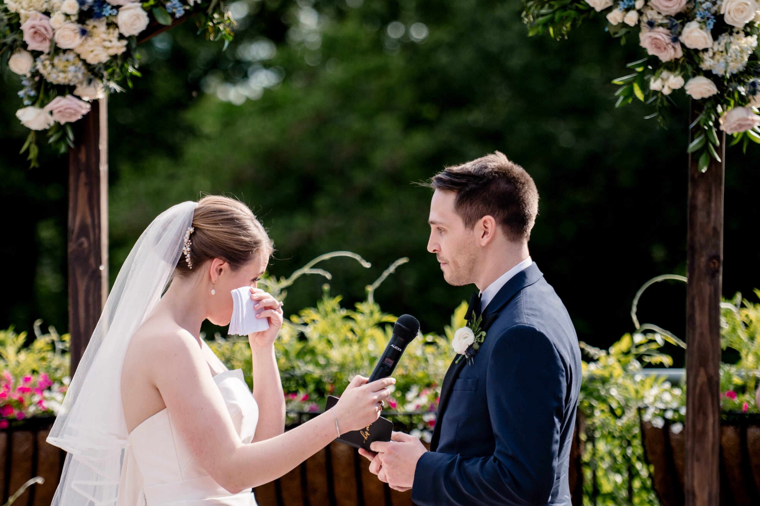 a woman wiping her eyes during her wedding speech at her wedding ceremony in a botanical garden