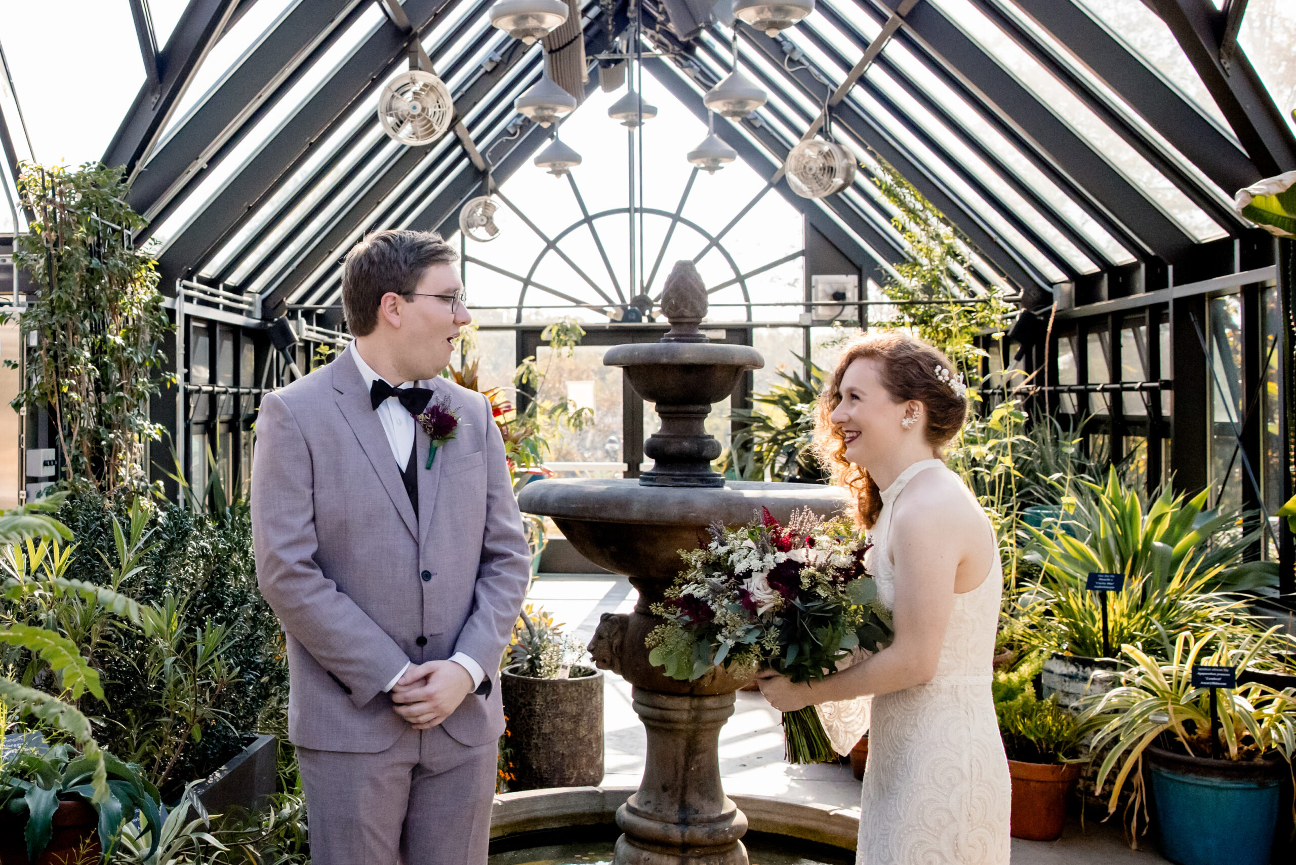 a couple sharing a first look at The Atrium at Meadowlark Botanical Gardens next to the fountain inside