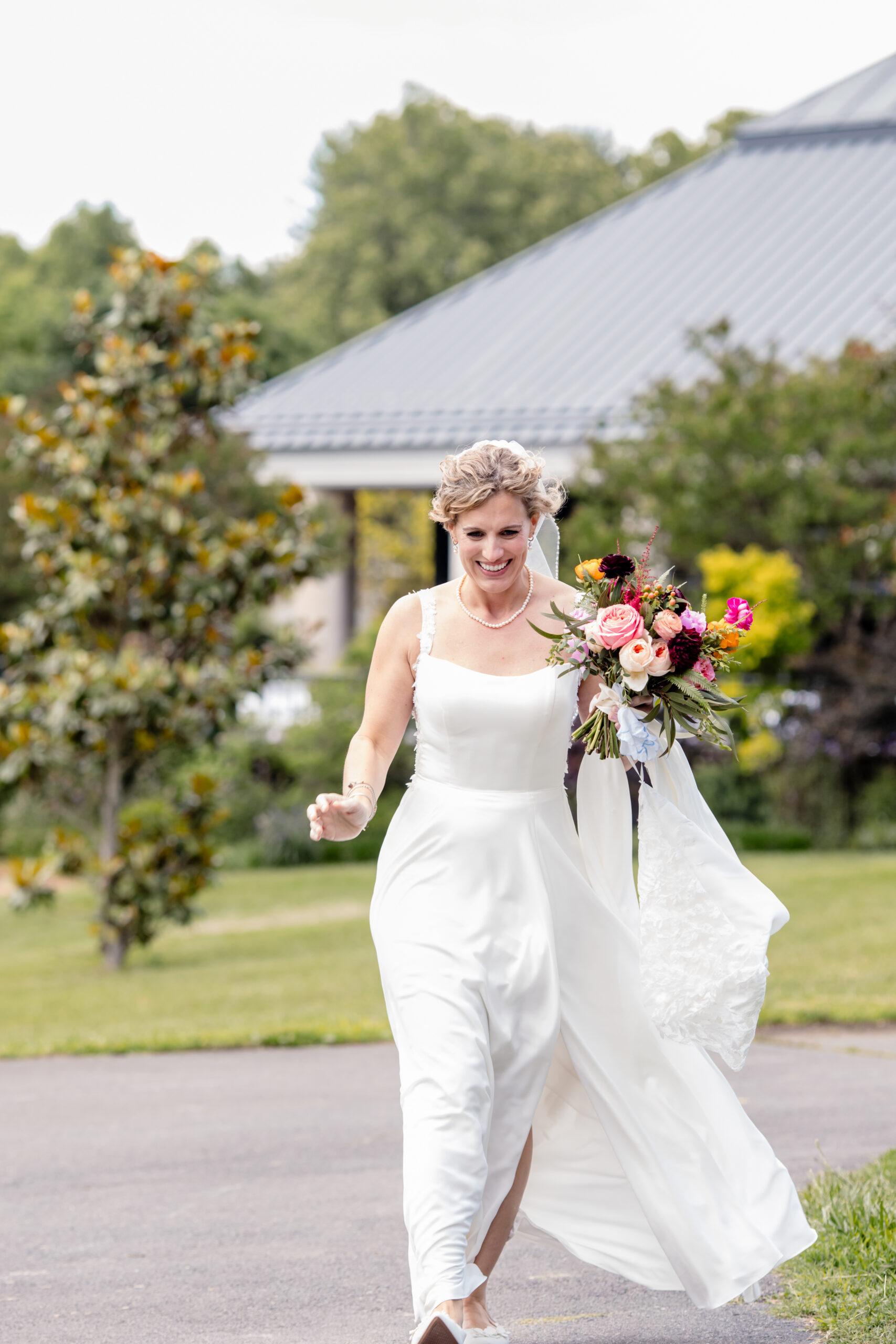 a woman in a wedding dress holding a bouquet and walking through a botanical garden
