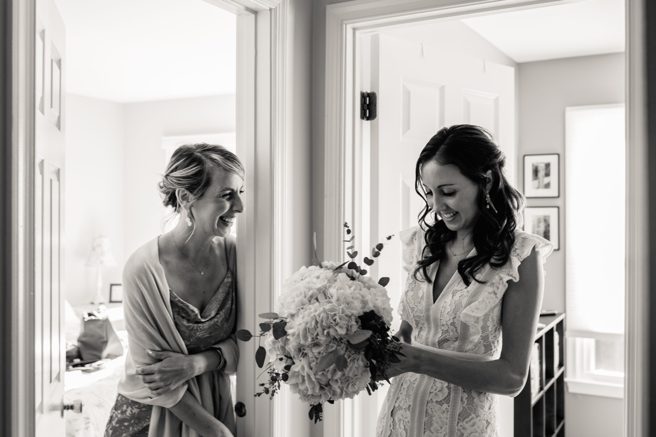 a bride talking to her bridesmaid and looking at a bouquet in her hands