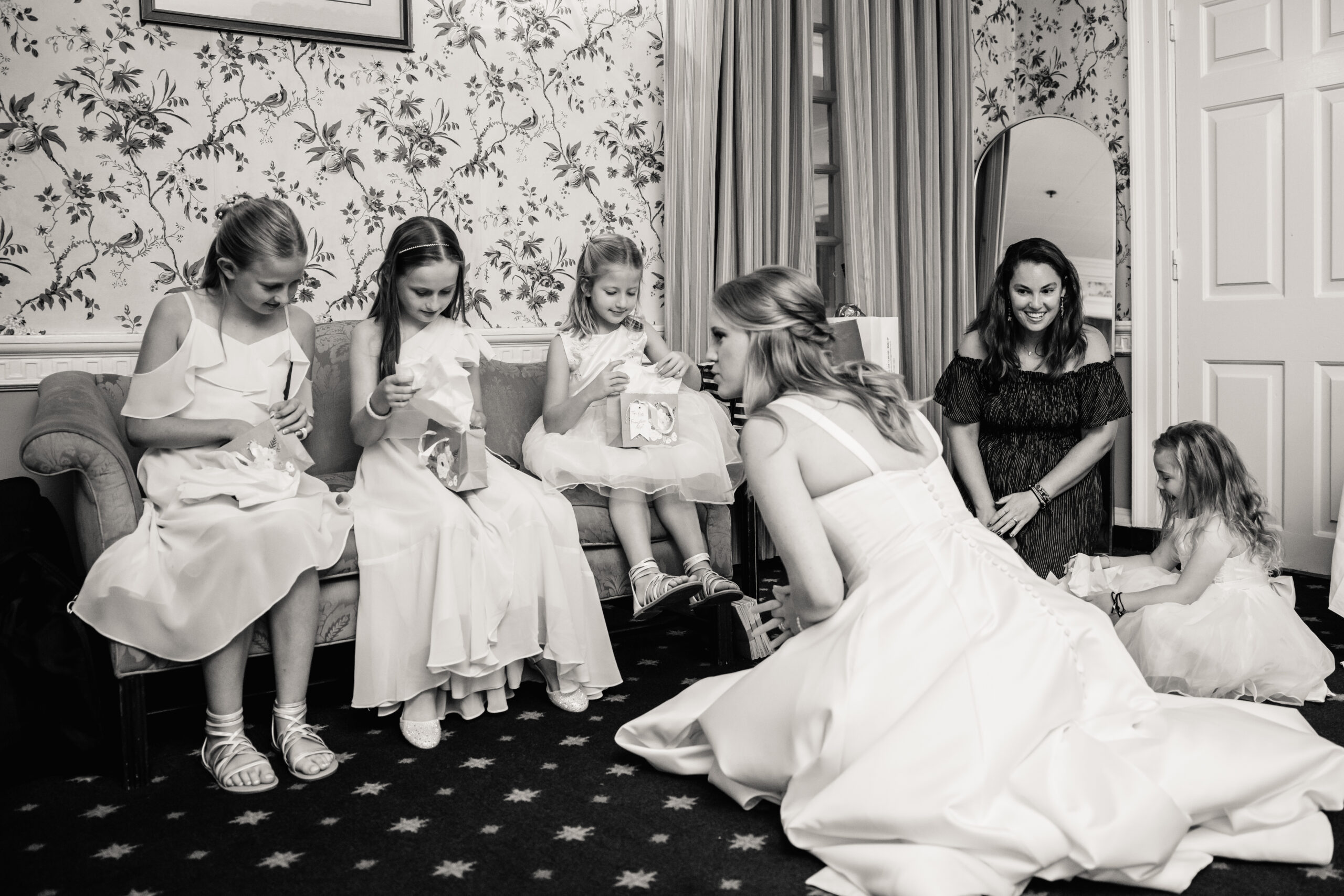 a bride sitting on the floor in a hotel room with her flower girls
