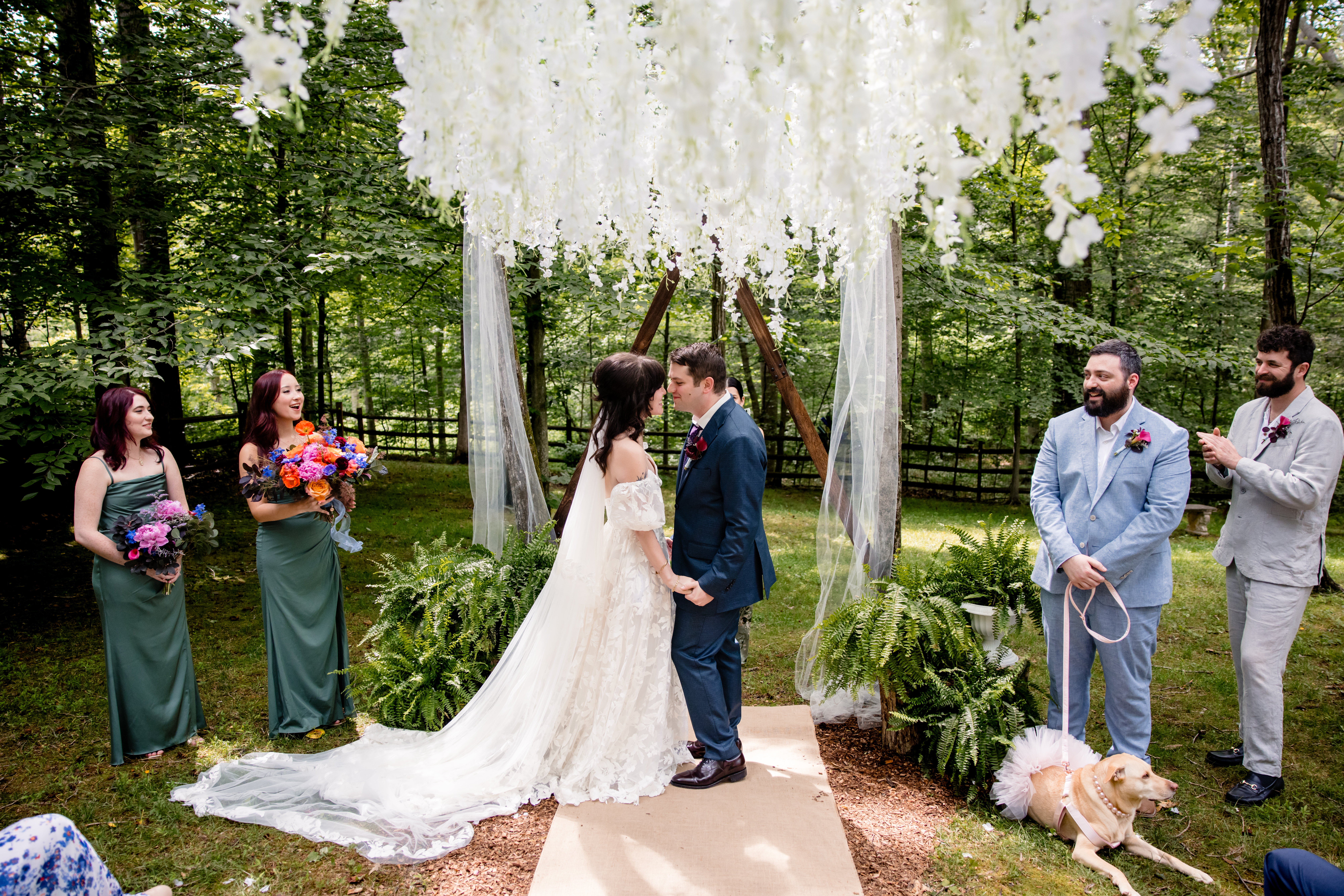 a bride and groom shaving their wedding ceremony and leaning in two kiss each other they both have a small wedding party that is standing next to them and cheering