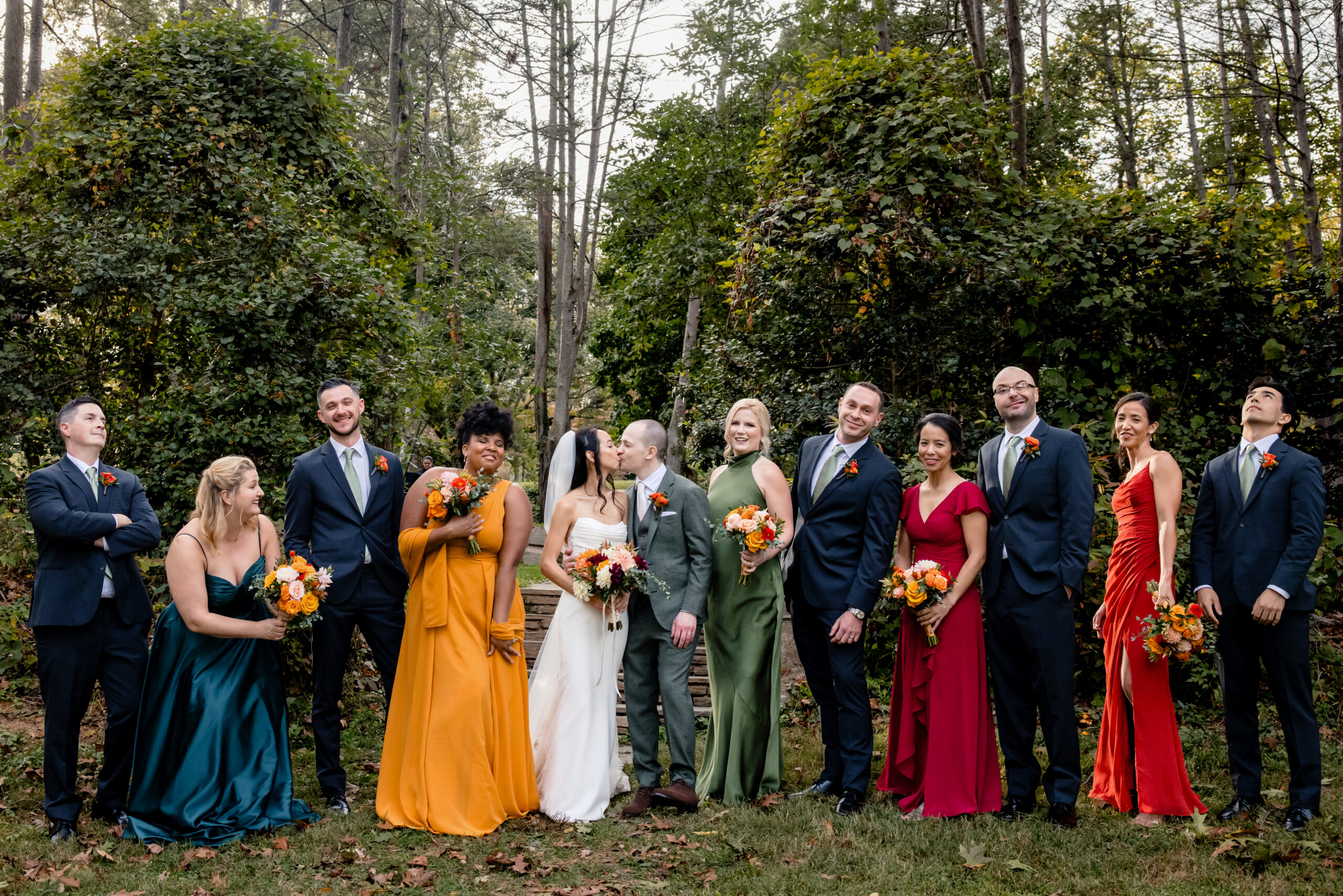 a bride and groom kissing at the woodend sanctuary and mansion in maryland while their bridal party stands next to them
