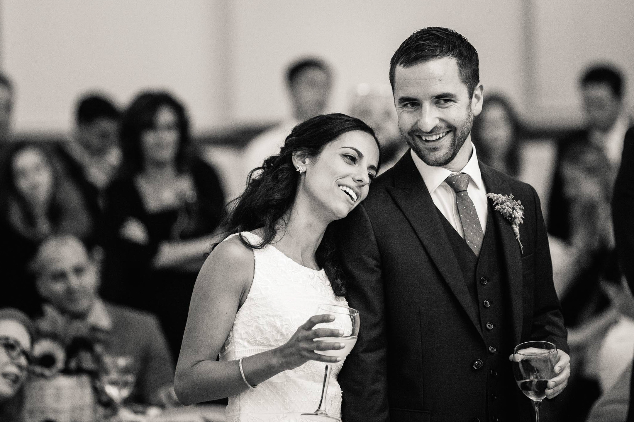 a bride leaning on her partner's shoulder and holding a glass of wine