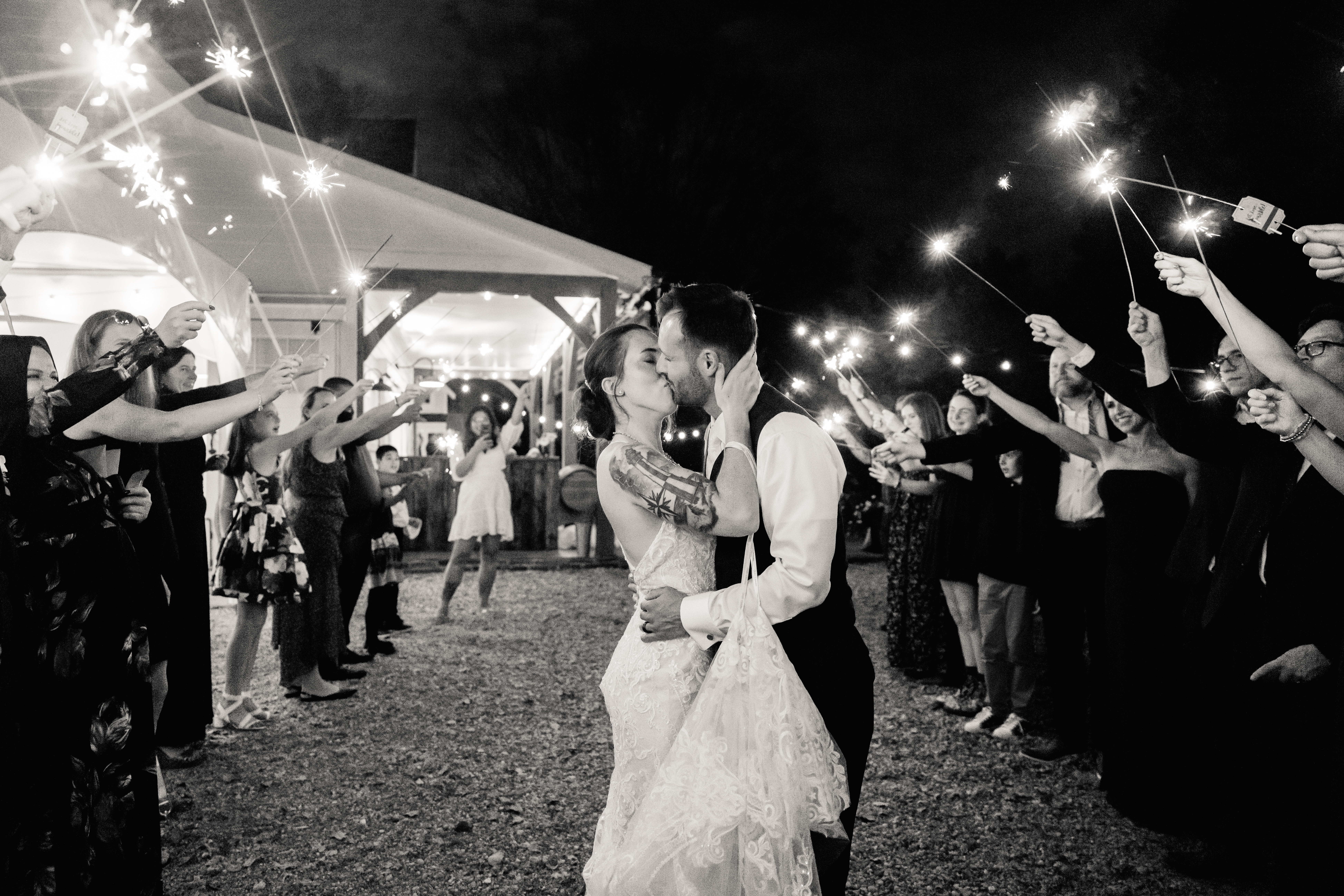 a bride and groom kissing during a sparkler exit