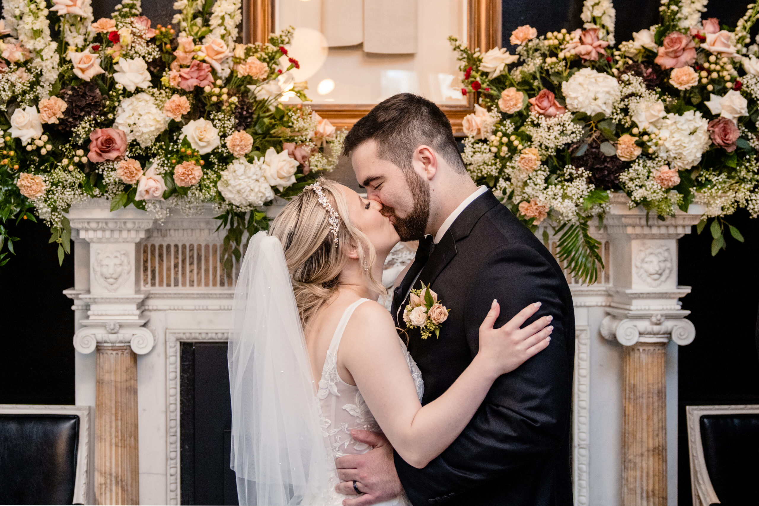 a bride and groom kissing in front of a fireplace