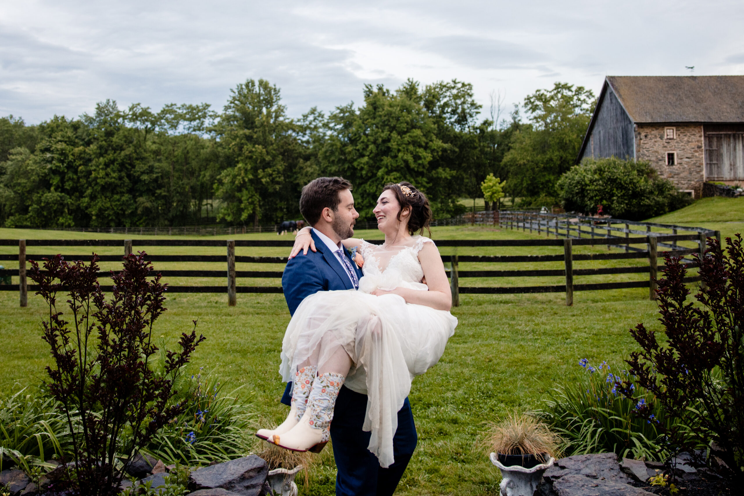 a groom holding his bride in his arms at a countryside wedding venue