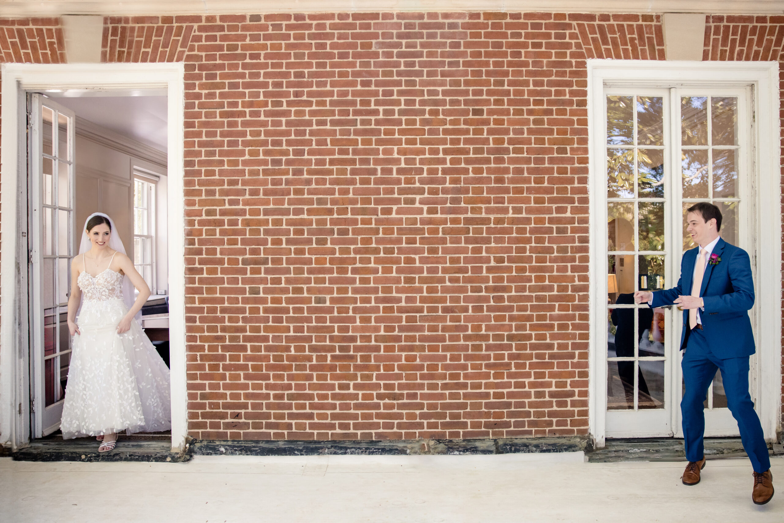 a bride and groom about to share a first look in front of a brick building