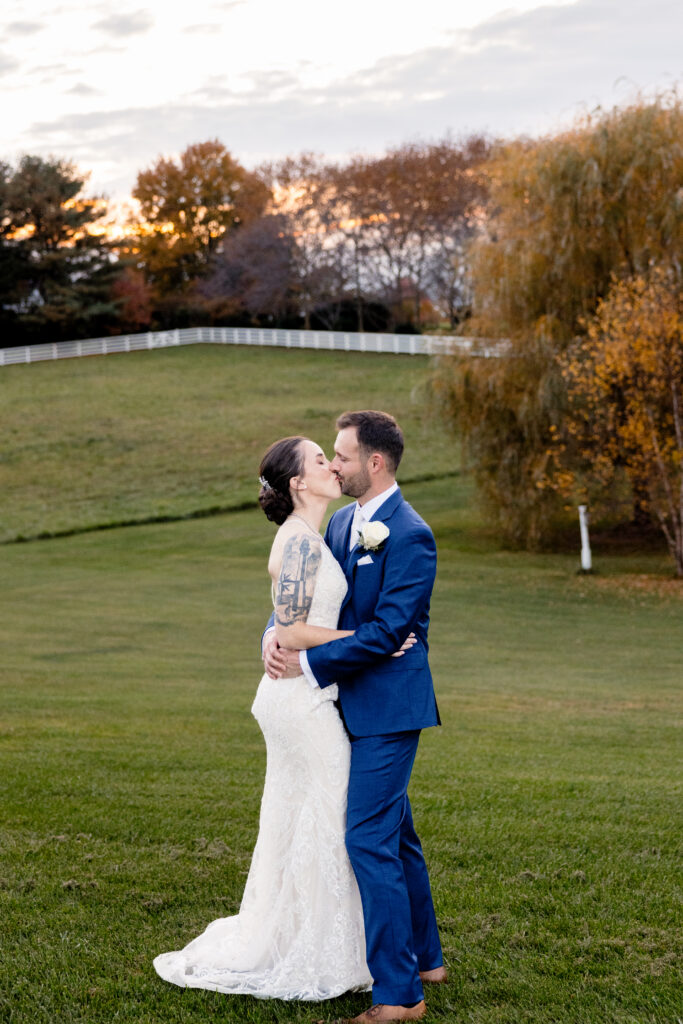 a bride and groom sharing a kiss and embracing at a countryside wedding venue