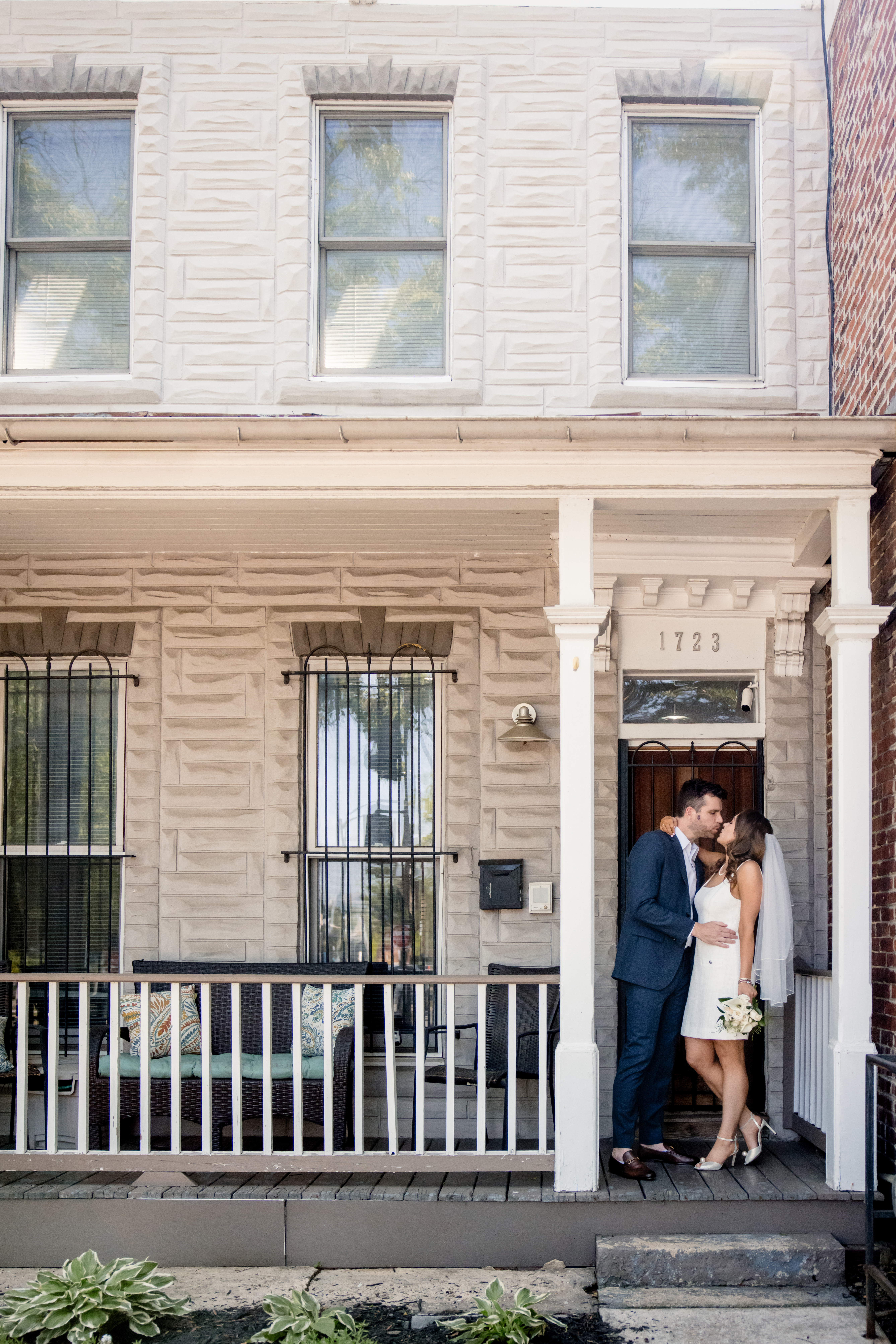 a bride and groom kissing on the steps in front of a house 