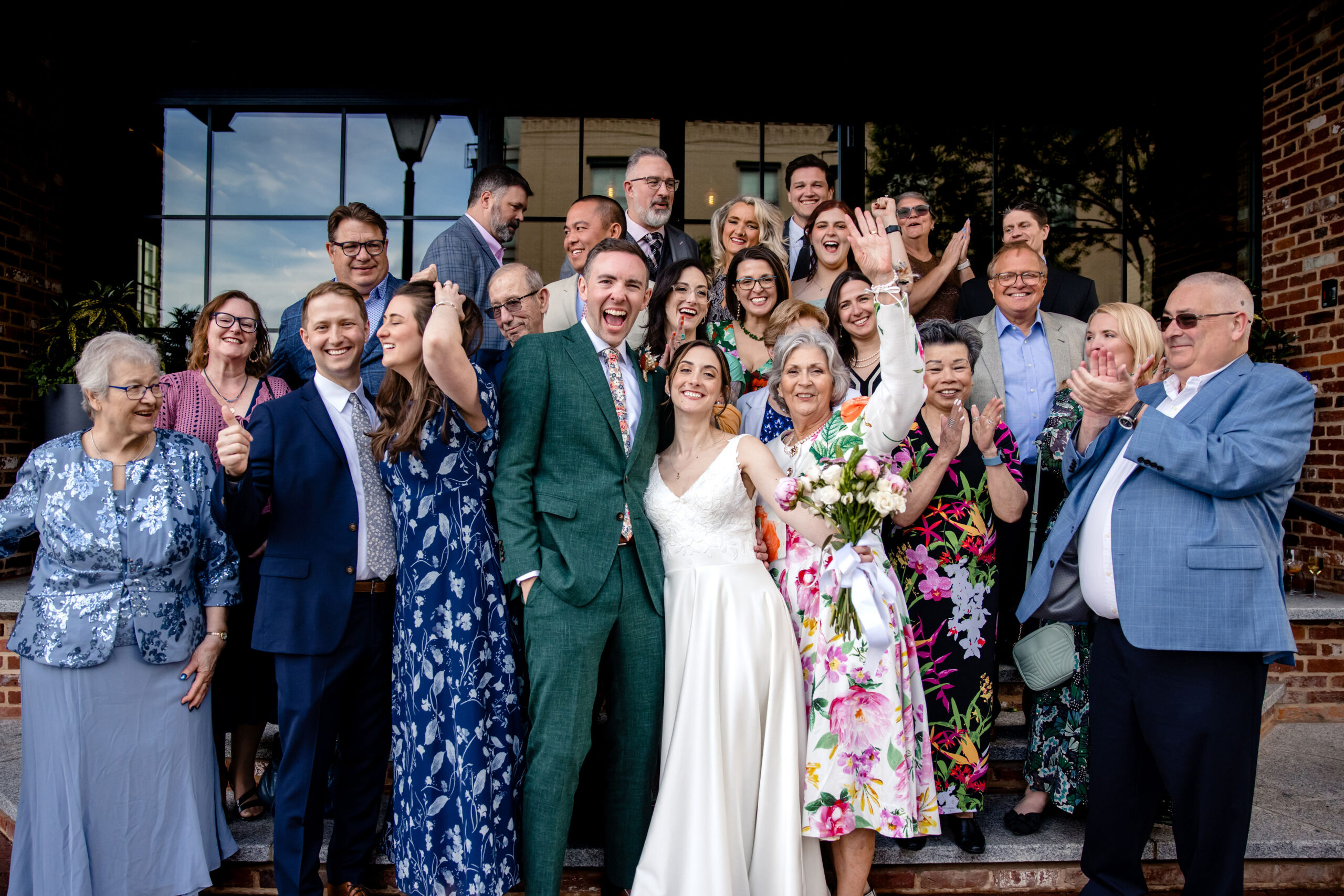a couple taking a photo with their family  in front of cooper mill on the day of ther wedding 