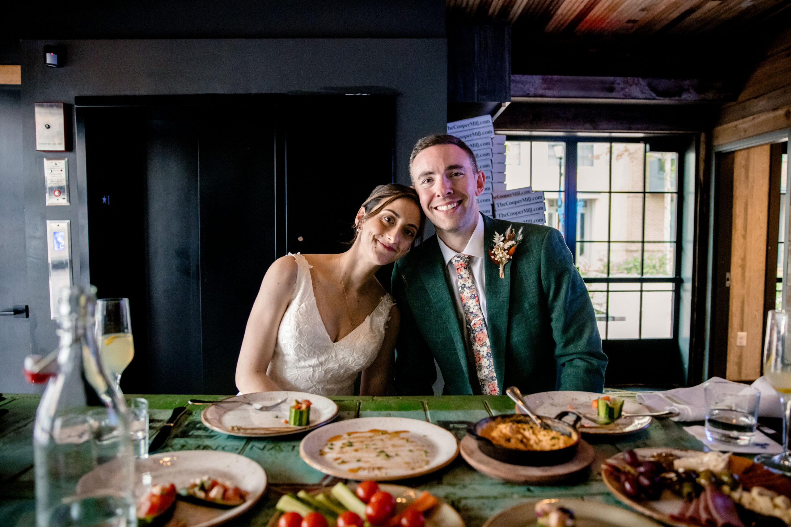 a man and woman taking a photo at their table on the day of their wedding 