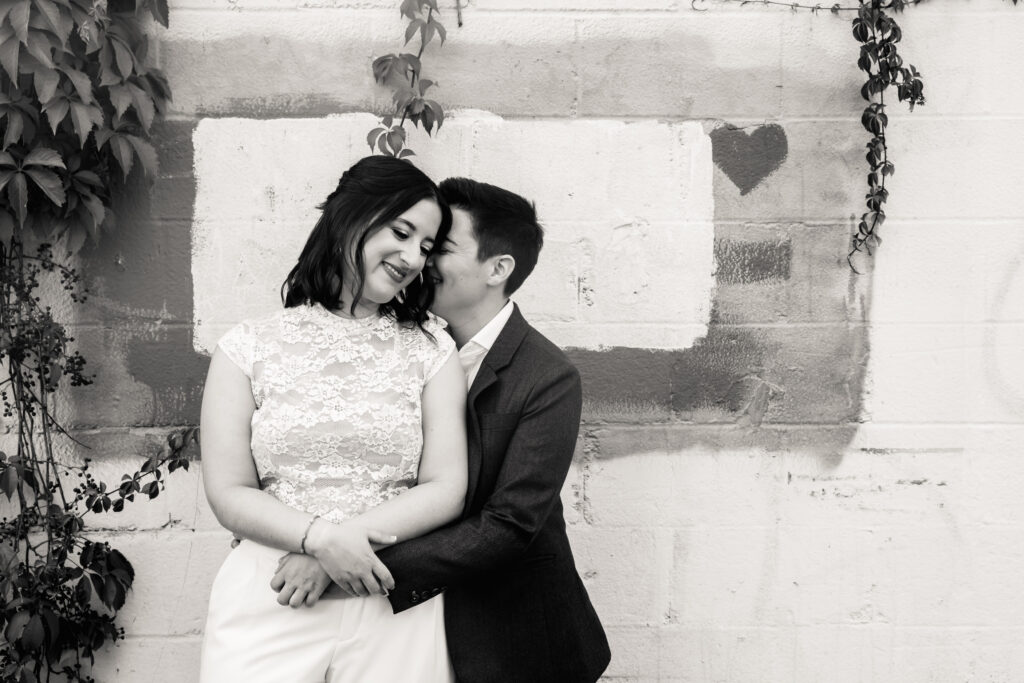 A person hugging their partner as they lean in to kiss their cheek 
