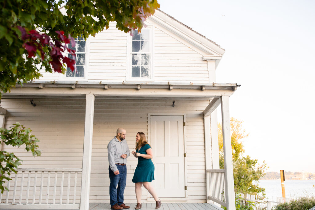 A couple laughing together as the stand on a porch 