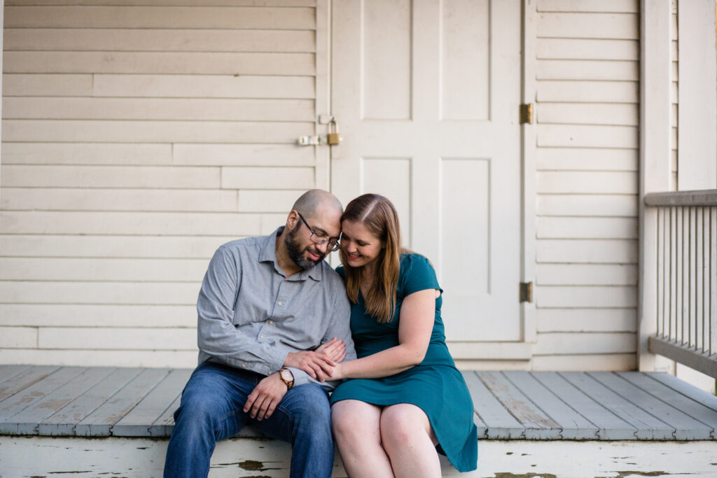 A couple sitting on a porch step together leaning into each other 