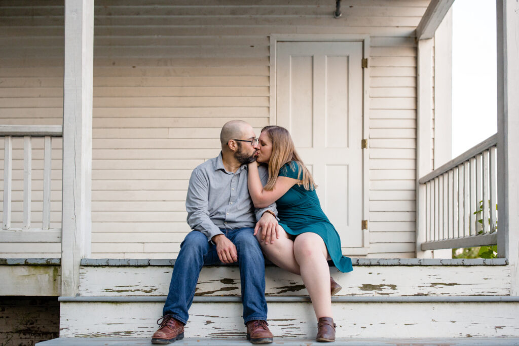 A couple sitting on a porch step together as they kiss 