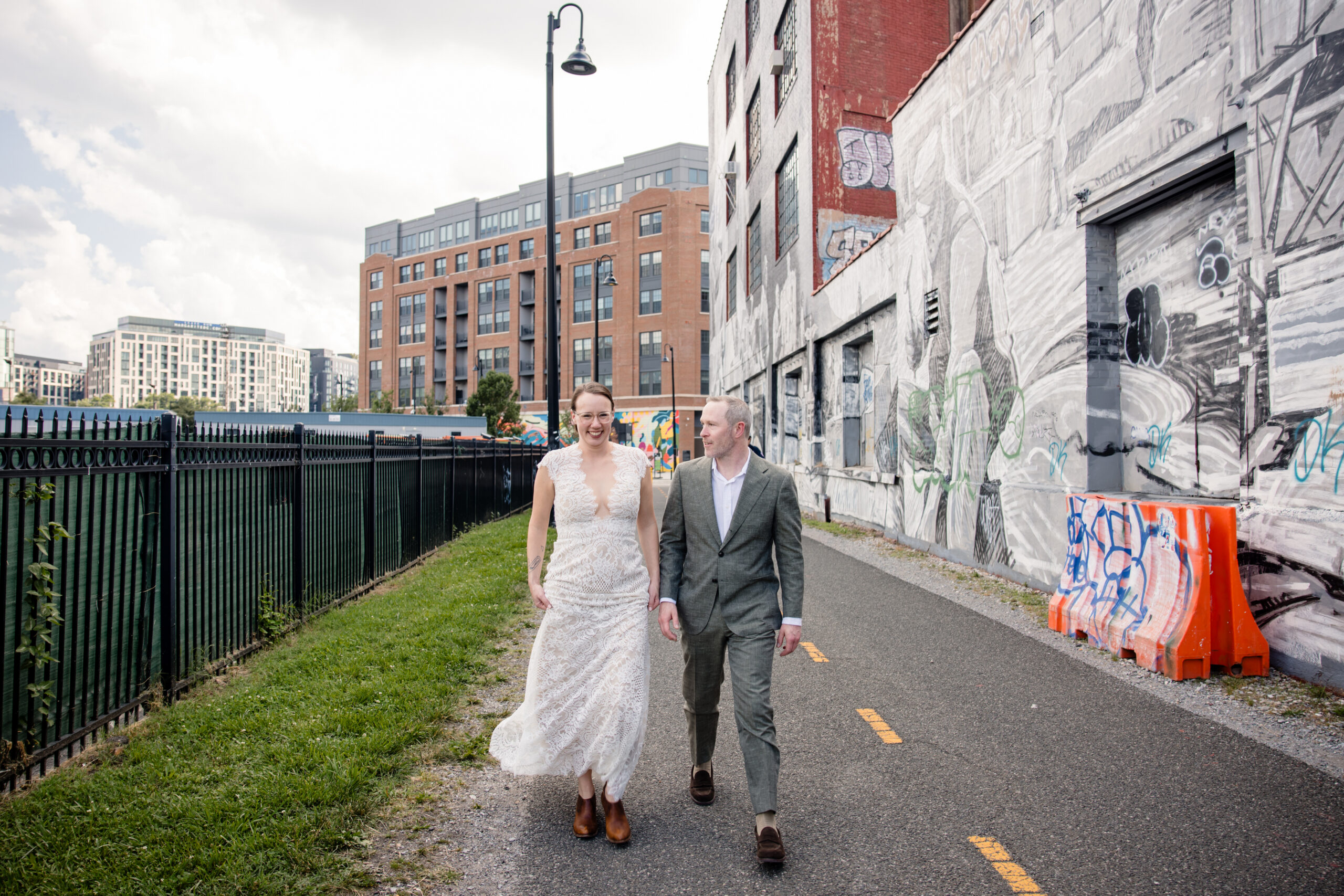 A couple holding hands and walking down a bike trail in a city during engagement photos in washington dc