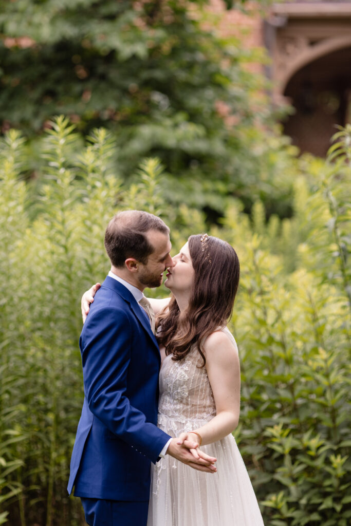 A couple dancing in a garden as they lean in to kiss 
