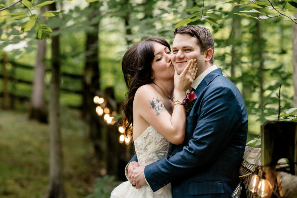 A newlywed kissing their partner's cheek as they smile 