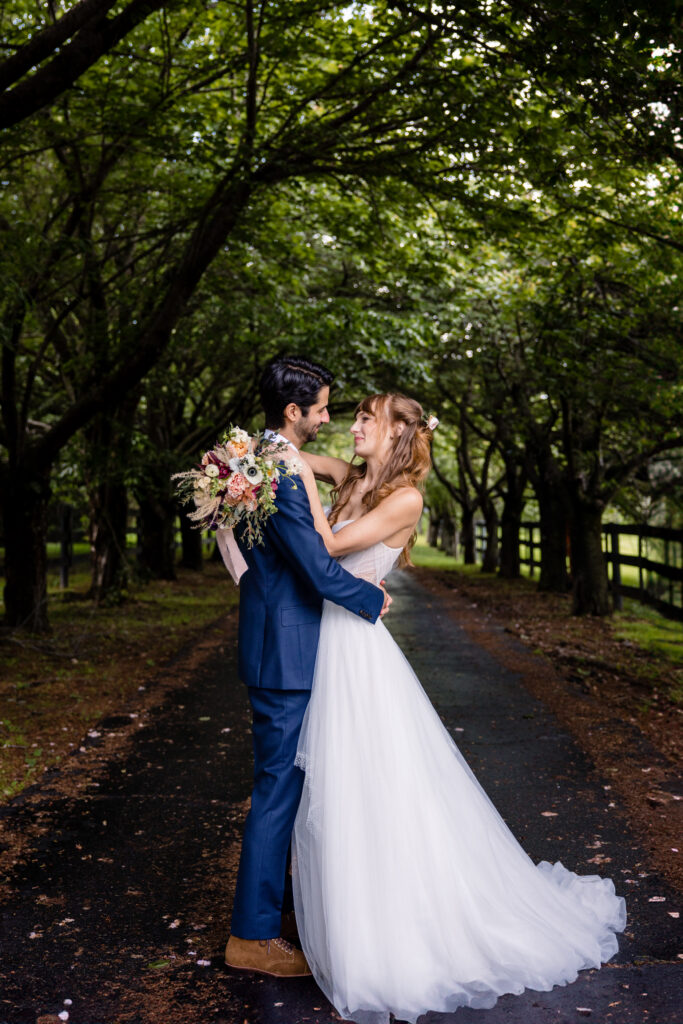 Newlyweds standing in a park with their arms around each other 
