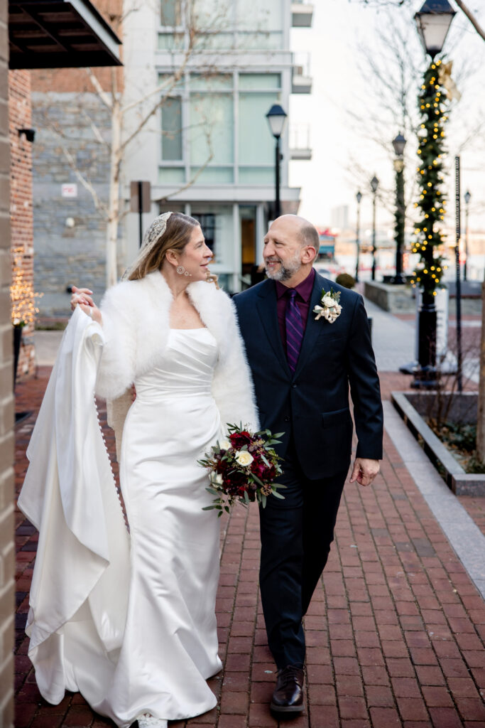 A newlywed couple walking down a city sidewalk 
